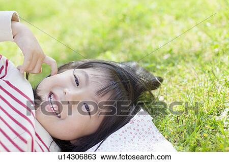 Stock Image - Girl lying down on picnic blanket. Fotosearch