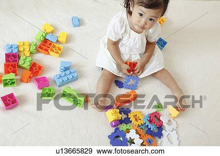 Stock Photo - Girl playing with plastic blocks. Fotosearch
