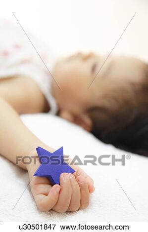 Stock Photo - Girl sleeping holding a star shaped toy. Fotosearch