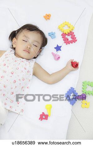 Girl sleeping holding a toy View Large Photo Image Stock Photo - Girl sleeping holding a toy. Fotosearch