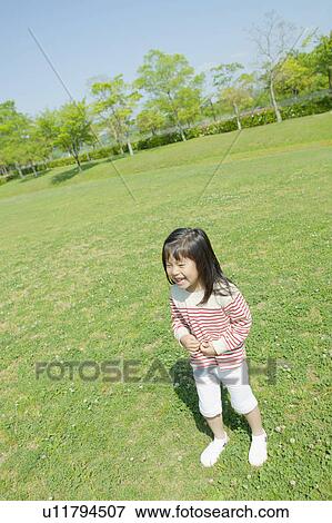 Stock Photo - Girl standing and smiling at a park. Fotosearch