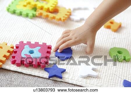 Girl trying to hold a piece of puzzle View Large Photo Image Stock Image - Girl trying to hold a piece of puzzle. Fotosearch