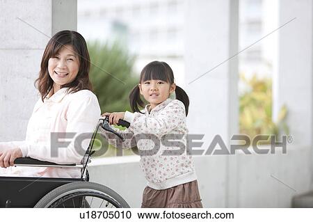 Stock Image - Granddaughter Pushing Grandmother on Wheelchair. Fotosearch