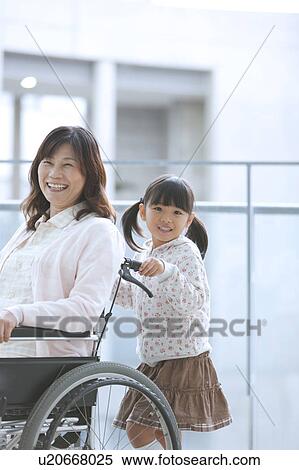 Stock Photography - Granddaughter Pushing Grandmother on Wheelchair. Fotosearch