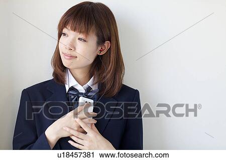 Stock Image - High School Student Listening Music With Mobile Phone and Smiling. Fotosearch