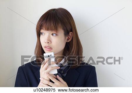 Stock Photography - High School Student Listening Music With Mobile Phone and Smiling. Fotosearch