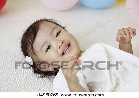 Stock Photo - Japanese Baby Girl Laying on Floor. Fotosearch