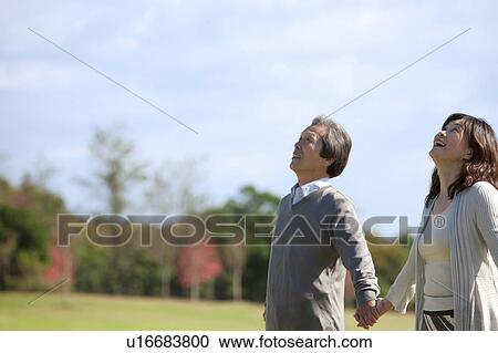 Stock Image - Mature Couple Holding Hands and Looking Up. Fotosearch