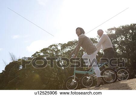 Stock Photograph - Mature couple on bicycle looking up. Fotosearch