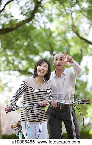 Stock Photography - Mature couple on bicycle looking up. Fotosearch