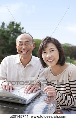 Mature couple using laptop outdoors View Large Photo Image Stock Image - Mature couple using laptop outdoors. Fotosearch