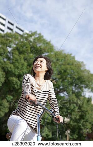 Stock Image - Mature woman riding a bicycle. Fotosearch
