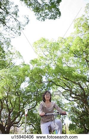 Mature woman riding a bicycle View Large Photo Image Stock Photograph - Mature woman riding a bicycle. Fotosearch