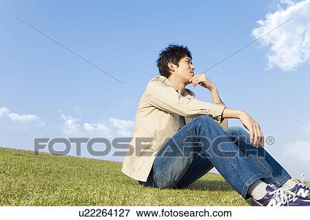 Stock Photo - Mid Adult Man Sitting on Grass and Thinking. Fotosearch