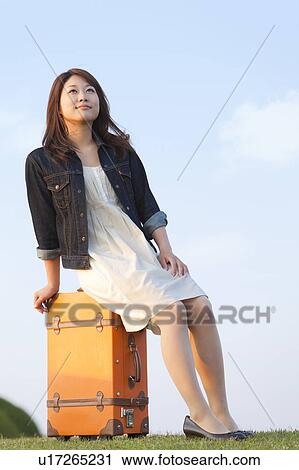 Stock Image - Mid Adult Woman Sitting on Suitcase. Fotosearch