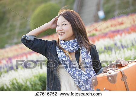 Stock Image - Mid Adult Woman with Suitcase in Field of Flowers. Fotosearch