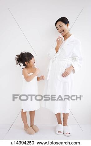 Stock Image - Mother and daughter brushing teeth. Fotosearch