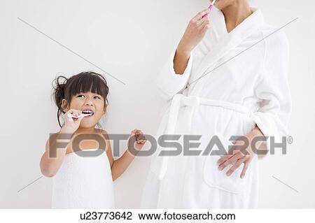 Stock Image - Mother and daughter brushing teeth. Fotosearch