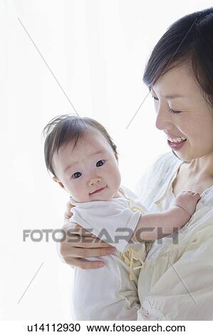 Stock Image - Mother carrying a baby. Fotosearch
