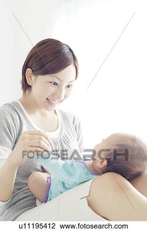 Stock Image - Mother Holding Newborn Baby on Her Lap. Fotosearch