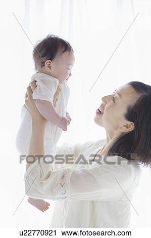 Mother picking up a baby View Large Photo Image Stock Image - Mother picking up a baby. Fotosearch