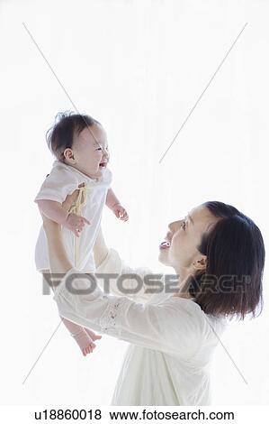 Stock Photo - Mother picking up a baby. Fotosearch