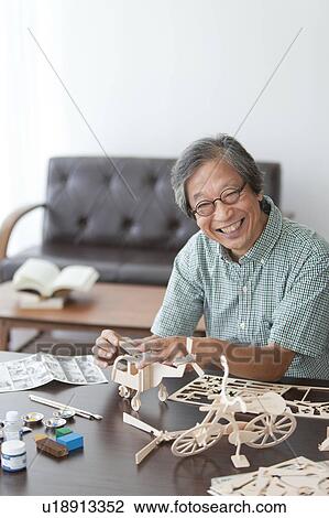 Stock Image - Senior Man Building Wooden Models. Fotosearch