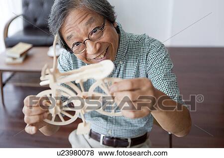Stock Photo - Senior Man Looking at Model Bicycle. Fotosearch