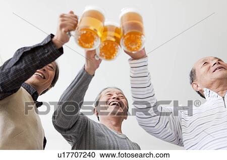 Stock Image - Three Senior Men Toasting with Pint. Fotosearch