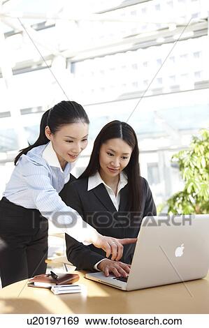 Stock Photo - Two Businesswomen Working at Desk. Fotosearch