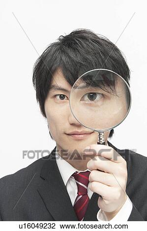 Stock Image - Young Businessman Looking Through Magnifying Glass. Fotosearch