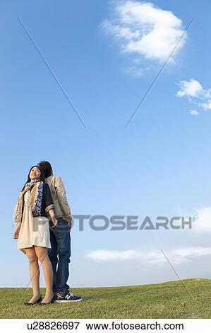 Young Couple Back to Back Against Blue Sky View Large Photo Image Stock Photo - Young Couple Back to Back Against Blue Sky. Fotosearch