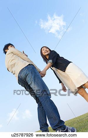 Stock Photograph - Young Couple Holding Hands and Looking Back. Fotosearch