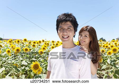 Stock Image - Young Couple in Sunflower Field. Fotosearch