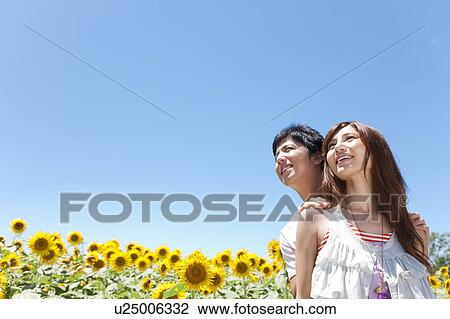 Stock Image - Young Couple in Sunflower Field. Fotosearch
