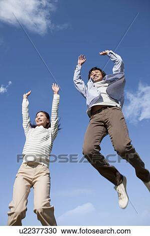 Stock Image - Young Couple Jumping in Mid Air. Fotosearch