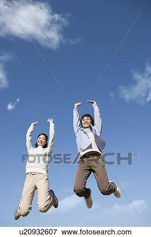 Stock Photo - Young Couple Jumping in Mid Air. Fotosearch