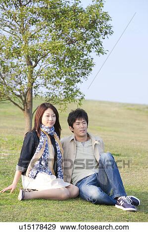 Stock Photo - Young Couple Sitting on Grass. Fotosearch