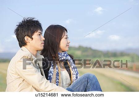 Stock Image - Young Couple Sitting Outdoors. Fotosearch