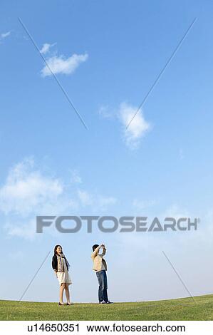 Stock Image - Young Couple Standing in Field. Fotosearch