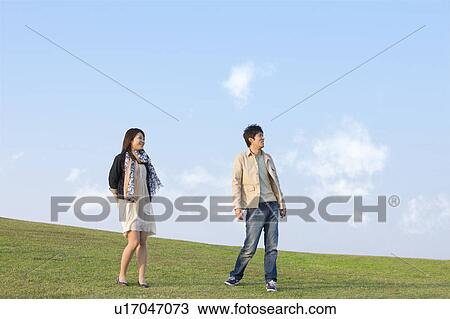 Stock Image - Young Couple Standing in Field. Fotosearch