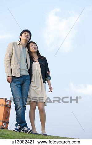 Stock Image - Young Couple with Suitcase Against Blue Sky. Fotosearch