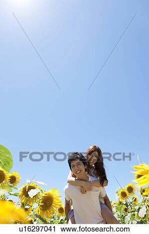 Stock Image - young couple woman man sunflowers sunflower field. Fotosearch