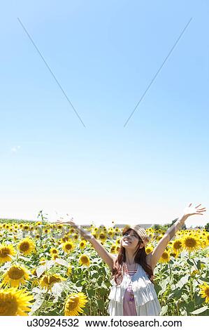 Stock Image - Young Woman in Sunflower Field. Fotosearch