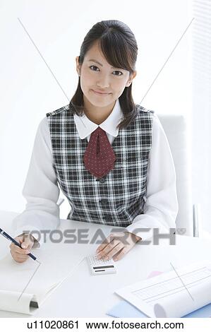 Stock Image - Young Woman Using Calculator. Fotosearch