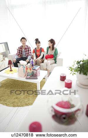 Stock Photo - Young Women Sitting on Sofa. Fotosearch