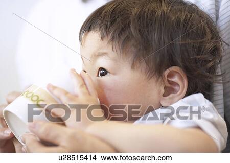 Baby getting help drinking from a cup View Large Photo Image Picture - Baby getting help drinking from a cup. Fotosearch