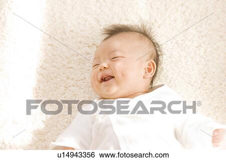 Stock Photograph - Baby lying down and smiling. Fotosearch