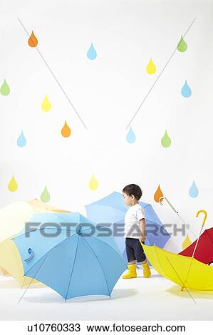 Stock Image - Boy Surrounded by Umbrellas in Rain. Fotosearch