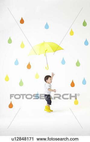 Stock Image - Boy Under Umbrella in Colourful Rain. Fotosearch